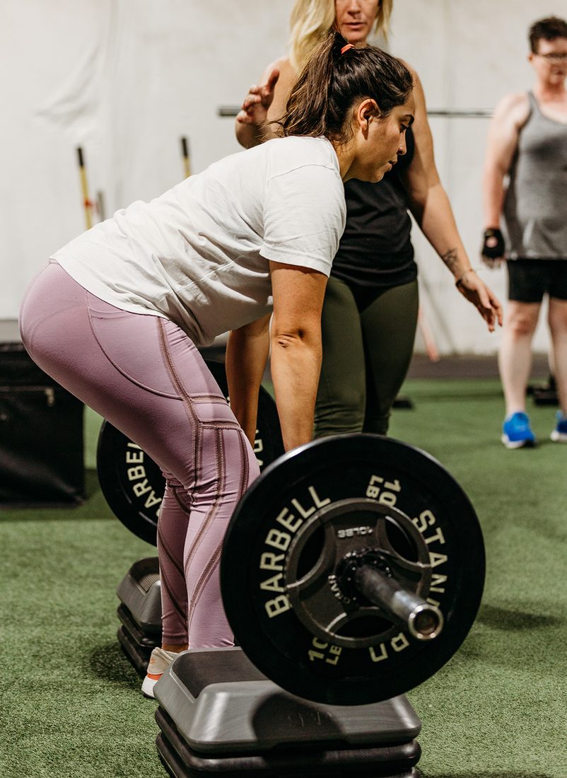 A TLAG coach working closely with a member during a strength exercise